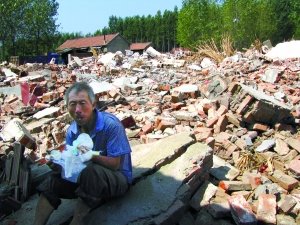 山东诸城枳沟二村，一名农民在瓦砾上吃午饭。